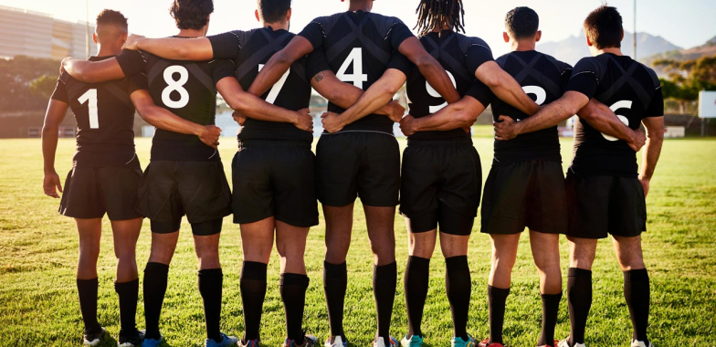 Rugby players in a line with arms round each other facing away from camera