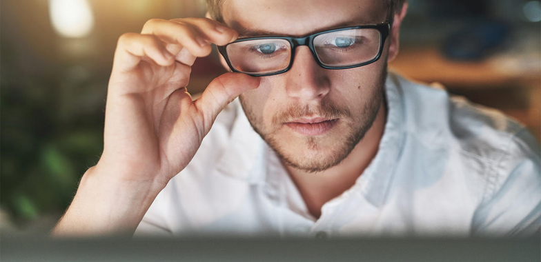 Man looking at computer screen while adjusting his glasses