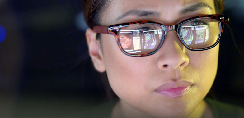 Close up of woman's face wearing glasses looking at a computer screen