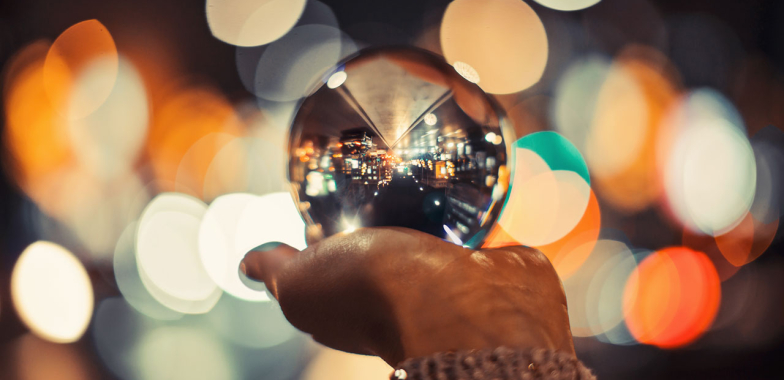 A hand with a crystal ball in it's palm with blurred lights in the background