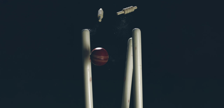 Cricket stumps being knocked over by a cricket ball