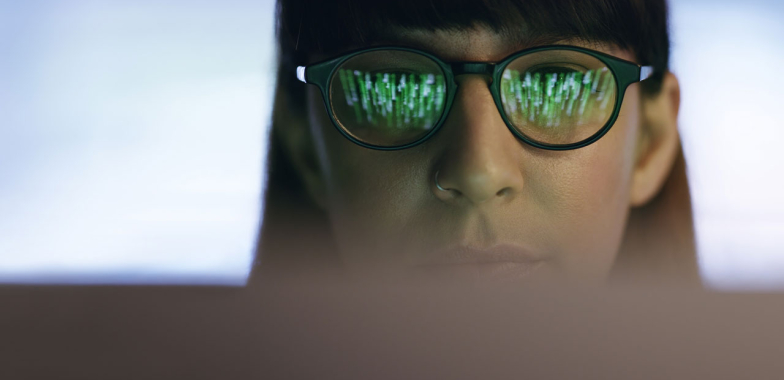 Close up of woman's face wearing glasses looking at a screen