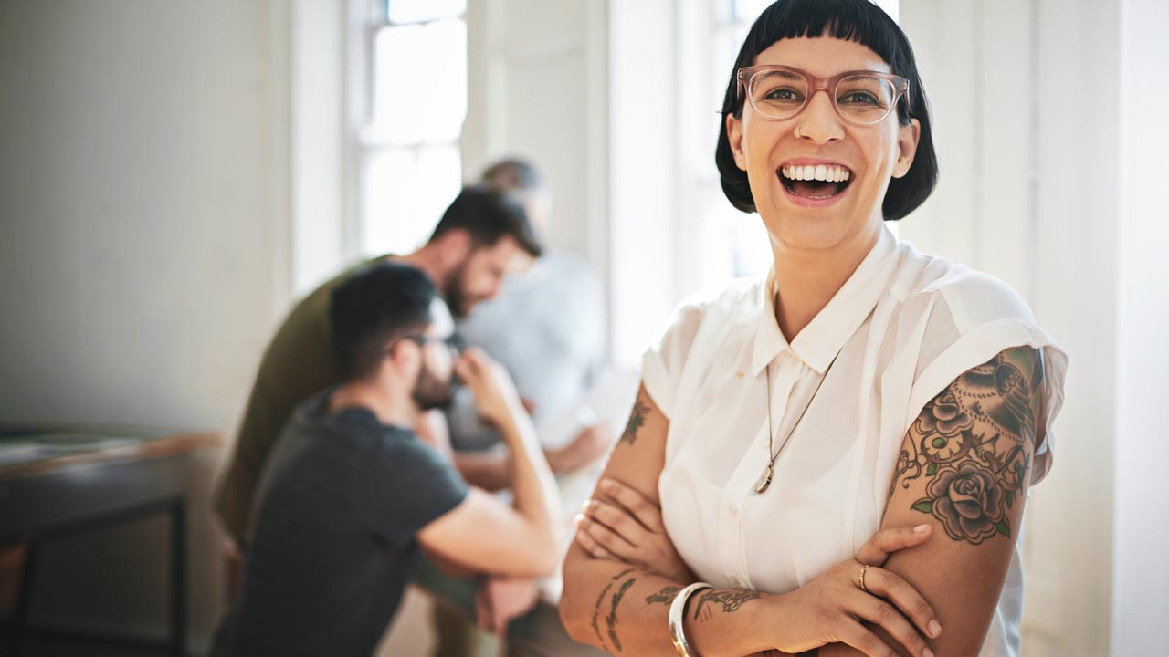 Woman smiling at camera with work colleagues in background working