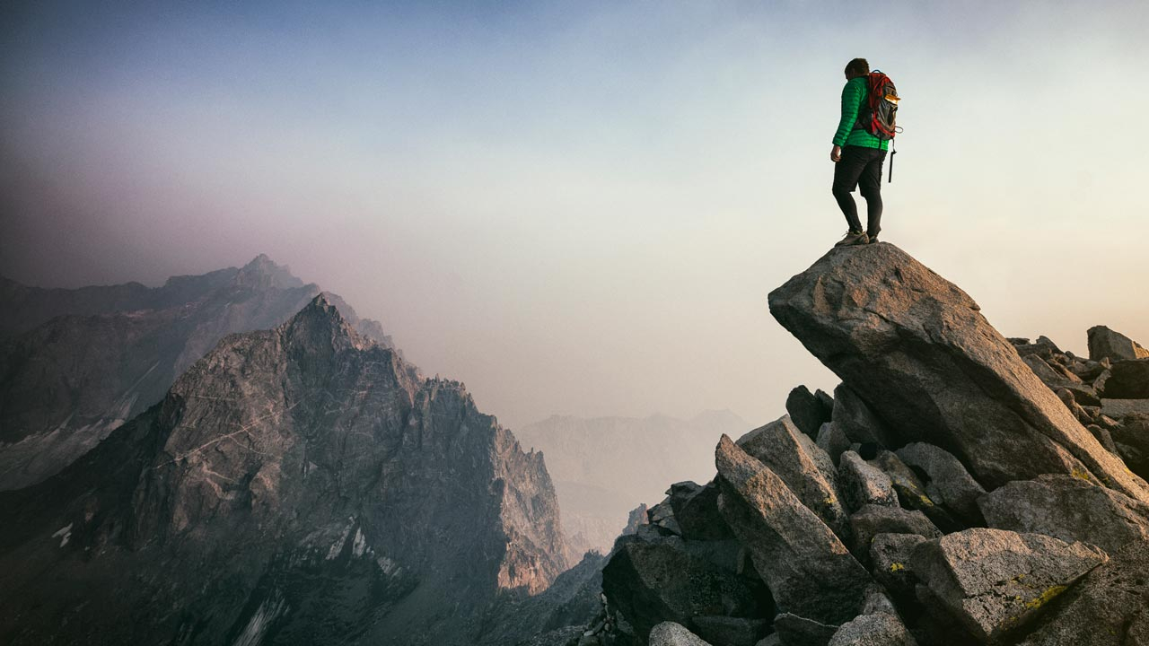 Man standing on a rocky outcrop high in the mountains 