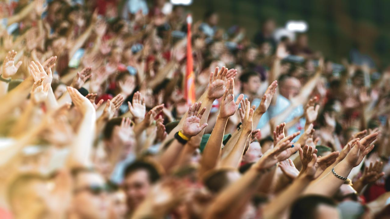Crowd of people at a convention with arms outstretched