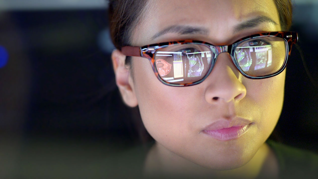 Close up of woman's face wearing glasses looking at a computer screen