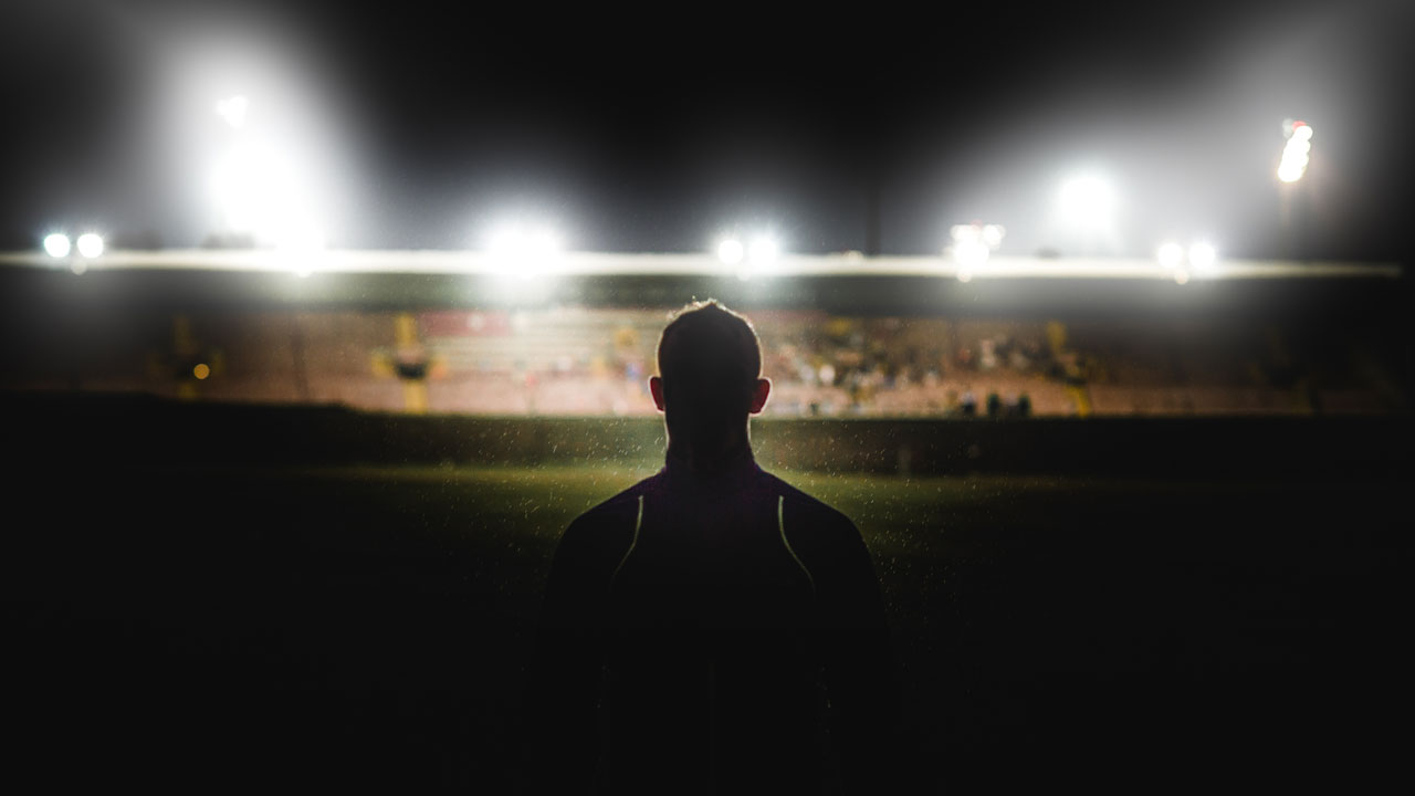 Outline of a rugby player in a stadium under lights