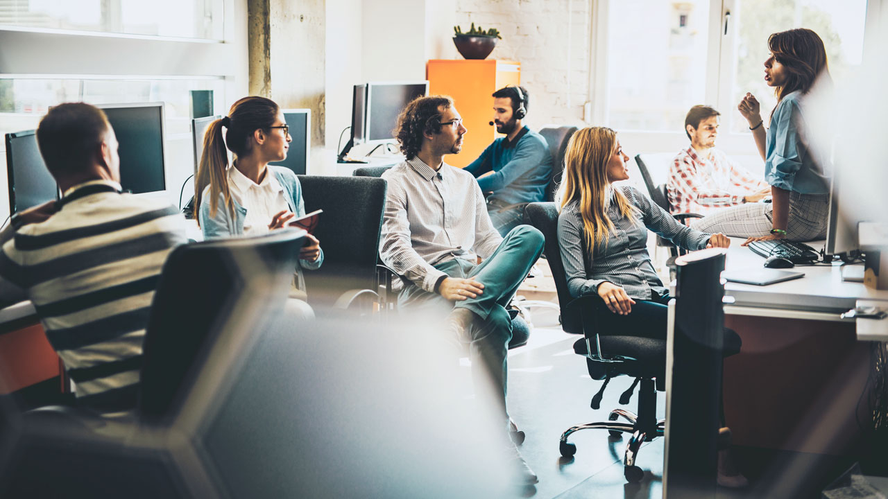 Group of office workers in office sitting on chairs talking