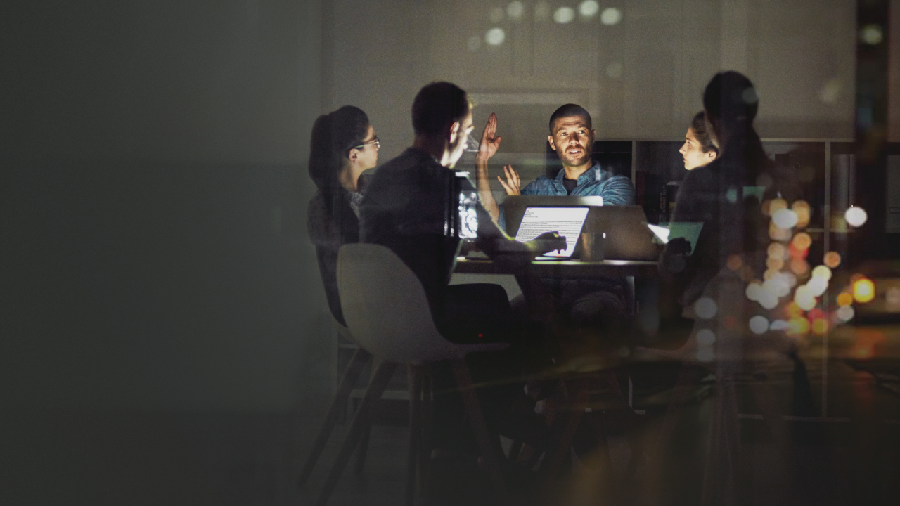 Group sitting around desk chatting in dim lighting